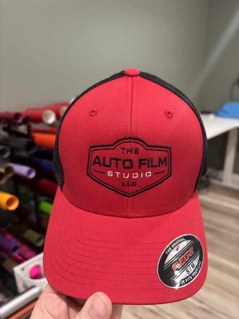 Red and black cap with The Auto Film Studio logo embroidered on the front