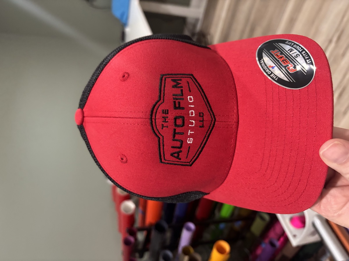 Red and black cap with a business logo embroidered on the front