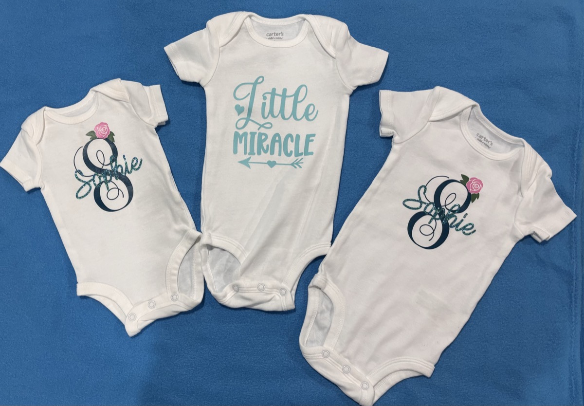 White baby onesies with personalized glitter monograms and a Little Miracle design
